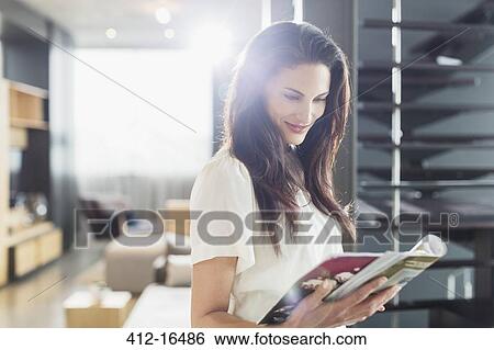 Smiling woman reading magazine at home View Large Photo Image Stock Photograph - Smiling woman reading magazine at home. Fotosearch