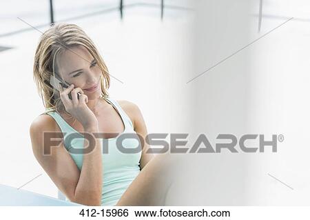 Stock Photograph - Smiling woman talking on cell phone on patio. Fotosearch