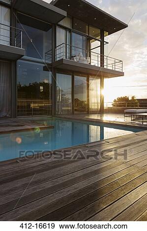 Stock Photo - Sun behind luxury house with swimming pool. Fotosearch