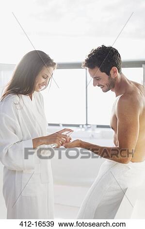 Stock Photo - Woman dispensing moisturizer in man's hand. Fotosearch