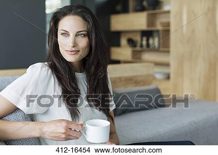 Woman drinking coffee in livingroom View Large Photo Image Picture - Woman drinking coffee in livingroom. Fotosearch