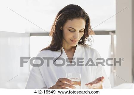 Woman in bathrobe taking medication in bathroom View Large Photo Image Stock Photo - Woman in bathrobe taking medication in bathroom. Fotosearch