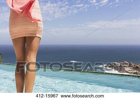 Woman in dress at poolside overlooking ocean View Large Photo Image Stock Photo - Woman in dress at poolside overlooking ocean. Fotosearch