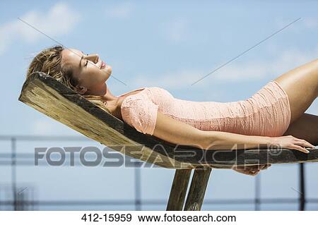 Woman in dress sunbathing on lounge chair View Large Photo Image Stock Photo - Woman in dress sunbathing on lounge chair. Fotosearch