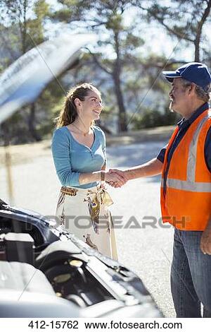 Stock Image - Woman shaking hands with roadside mechanic. Fotosearch