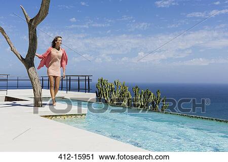 Woman standing at poolside overlooking ocean View Large Photo Image Stock Image - Woman standing at poolside overlooking ocean. Fotosearch