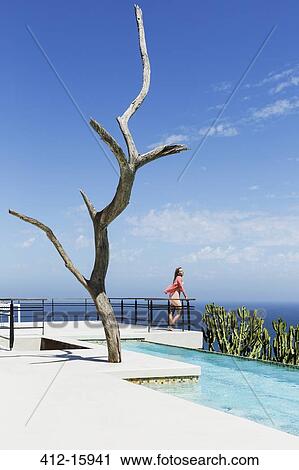 Woman standing on poolside balcony overlooking ocean View Large Photo Image Stock Image - Woman standing on poolside balcony overlooking ocean. Fotosearch