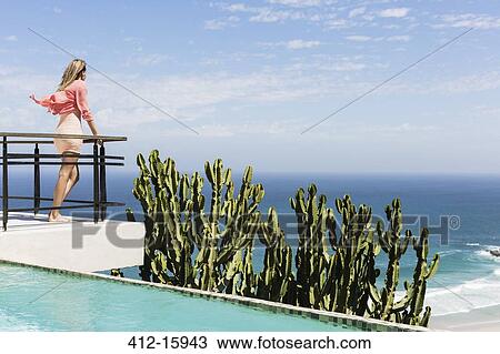 Woman standing on poolside balcony overlooking ocean View Large Photo Image Stock Image - Woman standing on poolside balcony overlooking ocean. Fotosearch