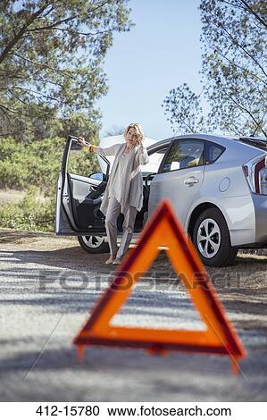 Woman talking on cell phone at roadside behind warning triangle View Large Photo Image Stock Image - Woman talking on cell phone at roadside behind warning triangle. Fotosearch