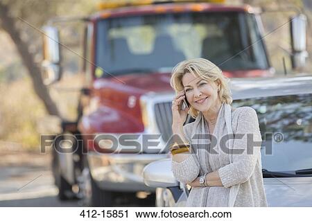 Woman talking on cell phone near tow truck at roadside View Large Photo Image Stock Image - Woman talking on cell phone near tow truck at roadside. Fotosearch