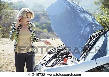 Woman talking on cell phone with automobile hood raised at roadside View Large Photo Image Stock Image - Woman talking on cell phone with automobile hood raised at roadside. Fotosearch
