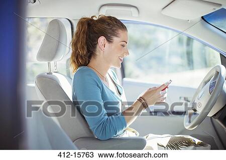 Woman texting with cell phone inside car View Large Photo Image Stock Image - Woman texting with cell phone inside car. Fotosearch