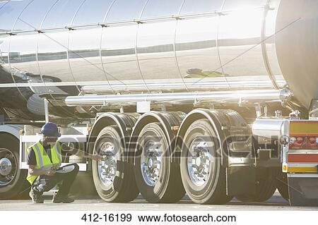 Stock Photo - Worker checking tire on stainless steel milk tanker. Fotosearch