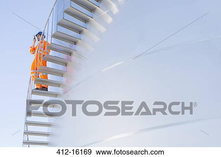 Worker using walkie-talkie on stairs along silage storage tower View Large Photo Image Stock Photo - Worker using walkie-talkie on stairs along silage storage tower. Fotosearch