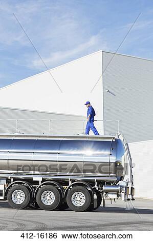 Worker walking on platform above stainless steel milk tanker View Large Photo Image Stock Photograph - Worker walking on platform above stainless steel milk tanker. Fotosearch