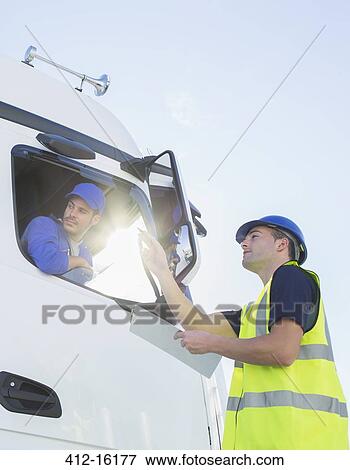 Stock Photo - Worker with clipboard directing truck driver. Fotosearch