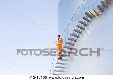 Worker with paperwork on stairs along silage storage tower View Large Photo Image Stock Photography - Worker with paperwork on stairs along silage storage tower. Fotosearch