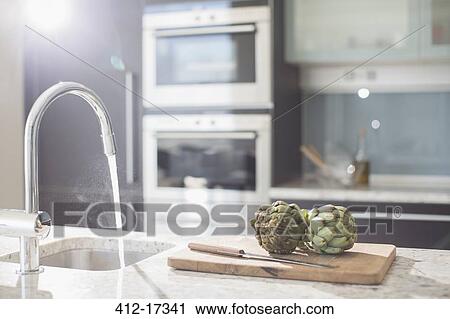 Artichokes on cutting board in modern domestic kitchen View Large Photo Image Stock Image - Artichokes on cutting board in modern domestic kitchen. Fotosearch