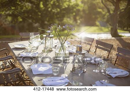 Bouquet and place settings on tranquil patio table View Large Photo Image Stock Photo - Bouquet and place settings on tranquil patio table. Fotosearch
