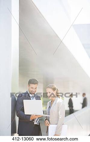 Stock Image - Business people using laptop outdoors. Fotosearch