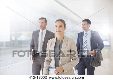 Stock Image - Business people walking in corridor. Fotosearch
