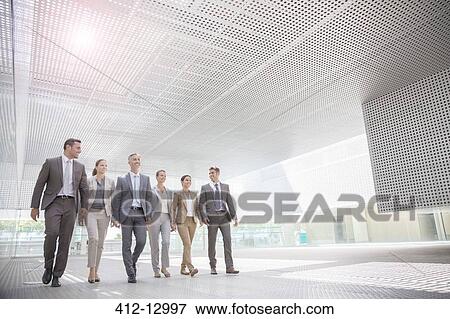 Stock Photo - Business people walking in modern courtyard. Fotosearch