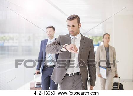 Stock Image - Business people with suitcases walking in corridor. Fotosearch