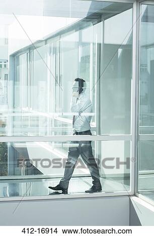 Picture - Businessman talking on cell phone in modern office. Fotosearch
