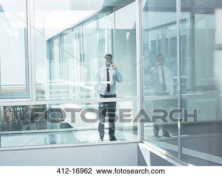 Businessman talking on cell phone in modern office View Large Photo Image Stock Image - Businessman talking on cell phone in modern office. Fotosearch