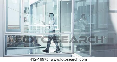 Stock Photography - Businessman talking on cell phone in office corridor. Fotosearch