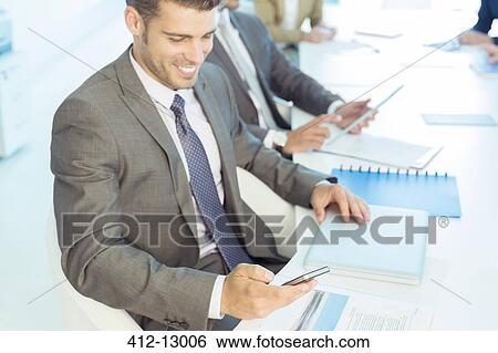 Businessman texting with cell phone in conference room View Large Photo Image Stock Photograph - Businessman texting with cell phone in conference room. Fotosearch