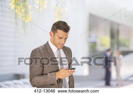 Businessman texting with cell phone outdoors View Large Photo Image Stock Photograph - Businessman texting with cell phone outdoors. Fotosearch
