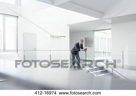 Businessman using digital tablet in corridor View Large Photo Image Picture - Businessman using digital tablet in corridor. Fotosearch