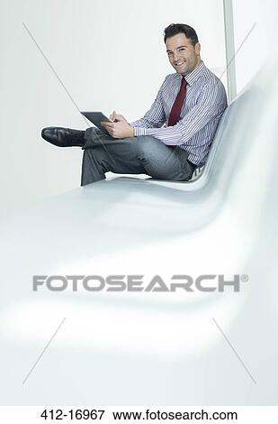 Stock Photo - Businessman using digital tablet in lobby. Fotosearch