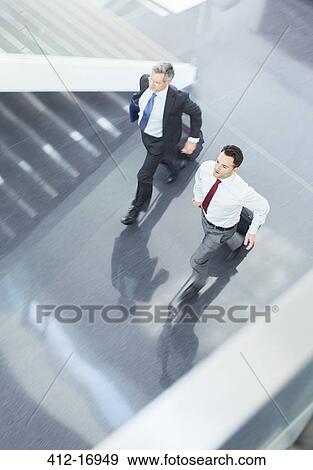 Stock Photo - Businessmen with suitcases running in lobby. Fotosearch