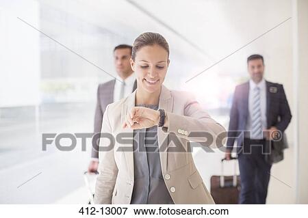 Businesswoman checking wristwatch in corridor View Large Photo Image Stock Photo - Businesswoman checking wristwatch in corridor. Fotosearch