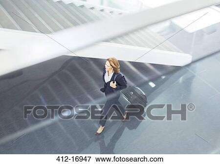Businesswoman pulling suitcase in lobby View Large Photo Image Stock Photo - Businesswoman pulling suitcase in lobby. Fotosearch