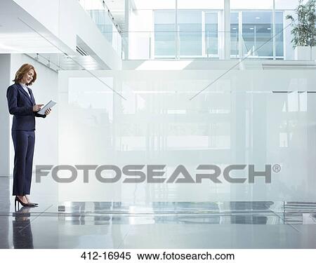 Businesswoman using digital tablet in modern office lobby View Large Photo Image Stock Photography - Businesswoman using digital tablet in modern office lobby. Fotosearch