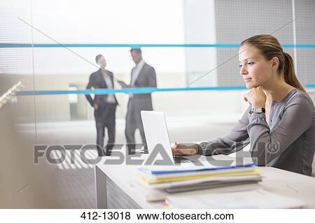Businesswoman using laptop at desk in office View Large Photo Image Stock Photo - Businesswoman using laptop at desk in office. Fotosearch