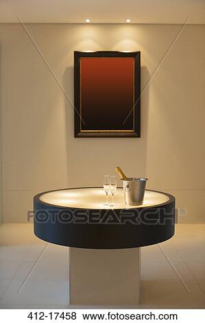 Stock Photo - Champagne in silver bucket next to champagne flutes in modern foyer. Fotosearch