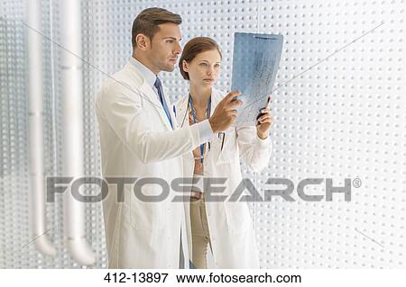 Doctors examining paperwork in hospital View Large Photo Image Stock Photo - Doctors examining paperwork in hospital. Fotosearch
