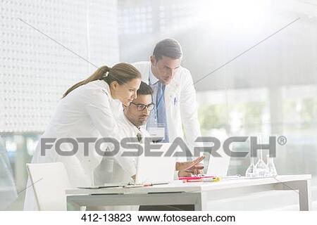 Stock Image - Doctors using laptop in laboratory. Fotosearch