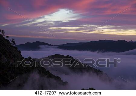 Stock Photo - Dramatic sky and fog among mountains. Fotosearch