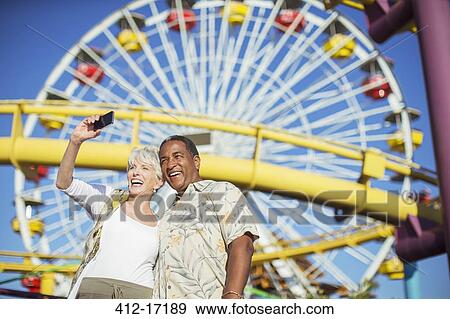 Enthusiastic senior couple taking selfie at amusement park View Large Photo Image Stock Photo - Enthusiastic senior couple taking selfie at amusement park. Fotosearch