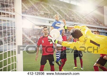 Stock Photograph - Goalie jumping for ball in soccer net. Fotosearch