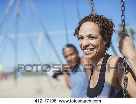 Happy couple on swings at playground View Large Photo Image Stock Photograph - Happy couple on swings at playground. Fotosearch