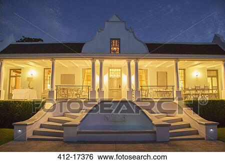 Stock Photograph - Luxury house with porch illuminated at night. Fotosearch
