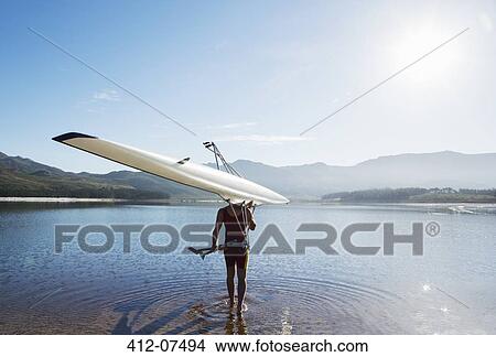 Picture - Man carrying rowing scull into lake. Fotosearch