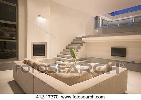Stock Image - Modern living room with balcony illuminated at night. Fotosearch