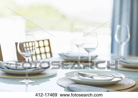 Stock Photo - Place settings on table in sunny dining room. Fotosearch